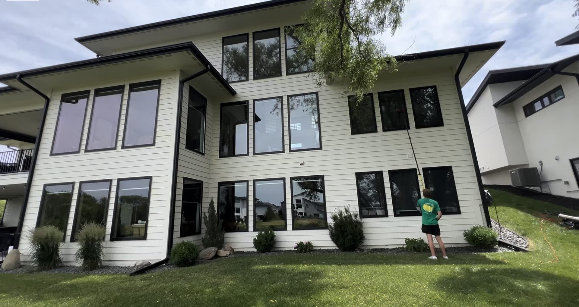 Window Boss technician using a water-fed pole on a modern two-story home